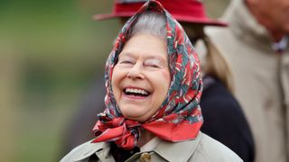The Queen laughing while wearing a red and blue headscarf at the Fell Class on day 3 of the Royal Windsor Horse Show in Home Park on May 15, 2015 in Windsor, England
