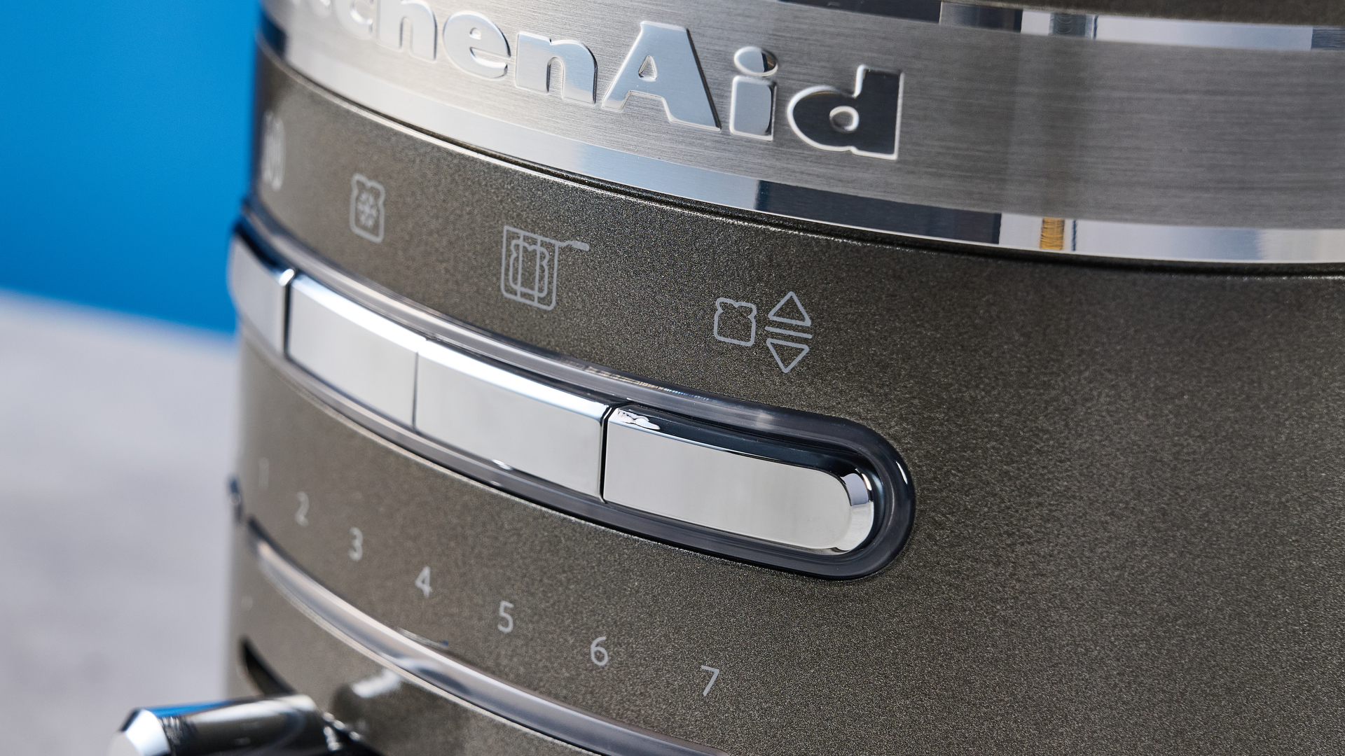 A photograph of the KitchenAid Pro Line toaster on a stone work surface with a blue and wooden background