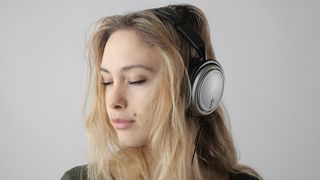 Self-isolation tips: Woman listening to music on headphone with a serene expression on her face