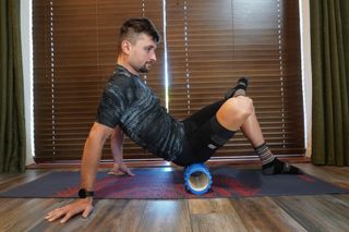 Image shows a cyclist using a foam roller.
