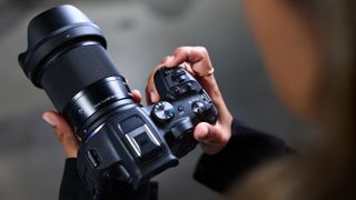 an over the shoulder shot of an individual holding a Canon camera with a Sigma RF mount lens