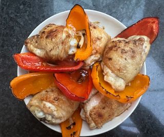 Roast chicken and bell peppers in a bowl on a kitchen counter.