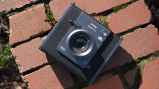 Fujifilm Instax Wide Evo sat on a red brick wall in the sun