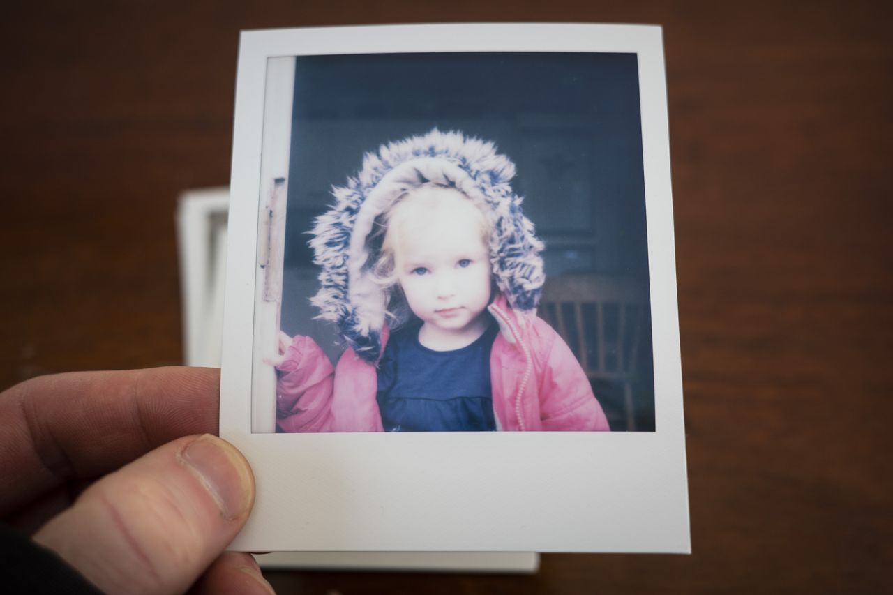 Polaroid SX70 instant print in the hand, color portrait