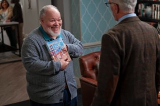 Stephen McKinley Henderson as Calbert, holding a book about the Golden Gate Bridge with the title "Gateway to the Pacific", in episode 108 of A Man on the Inside.