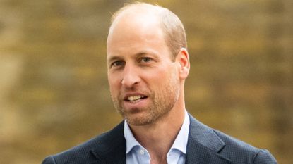 Prince William wearing a suit in front of a brick wall