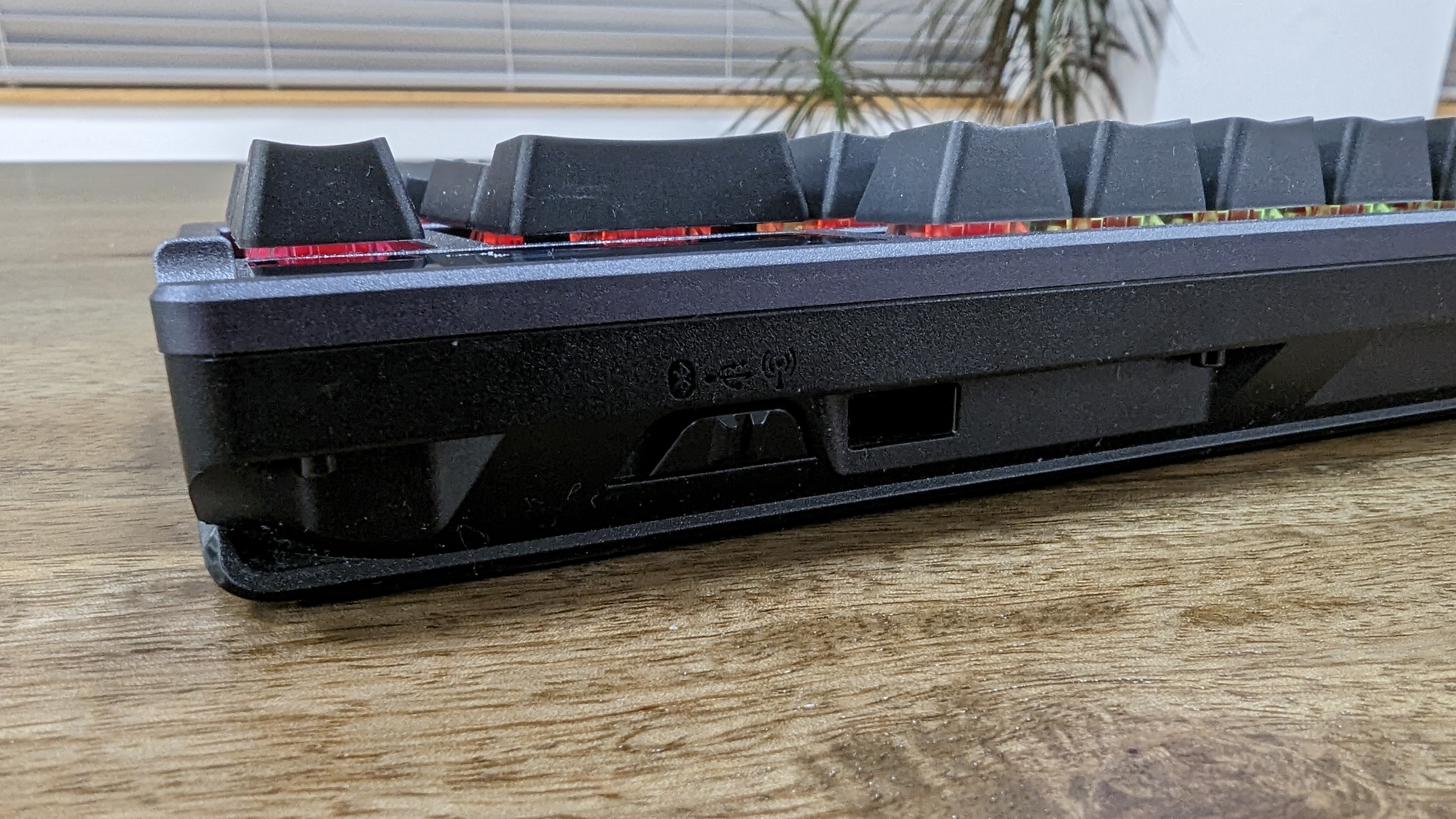 Asus ROG Azoth wireless gaming keyboard with RGB lighting on a wooden desk