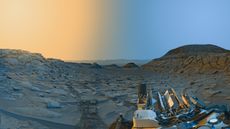 A robotic rover sits in the foreground on a rocky gray terrain with a half yellow and half blue sky in the background