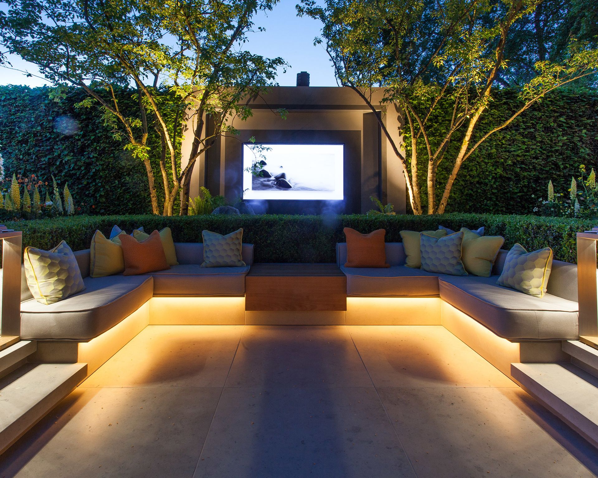 Under-seat outdoor lighting on a sunken outdoor living room area with a TV screen