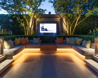 Under-seat outdoor lighting on a sunken outdoor living room area with a TV screen