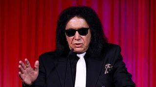Gene Simmons speaking in front of a red curtain