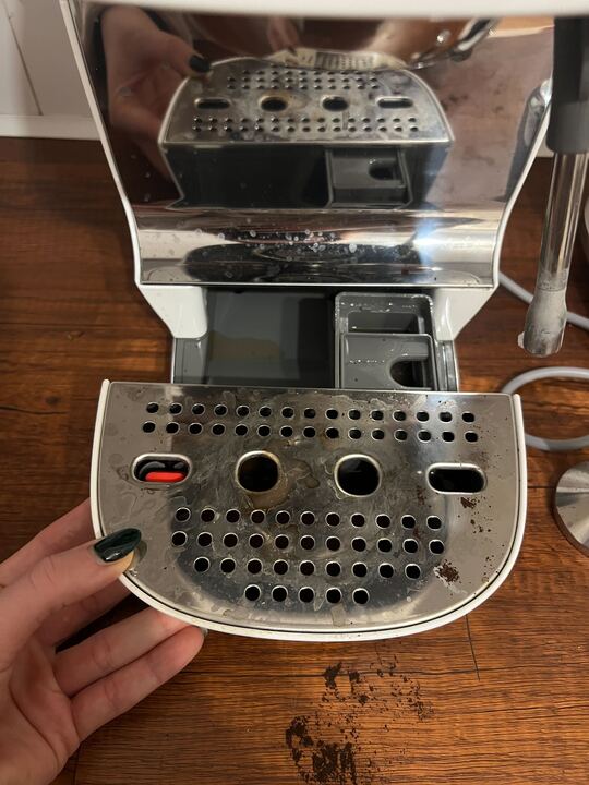 Image of a dirty tray that is slid open on a Smeg coffee machine.