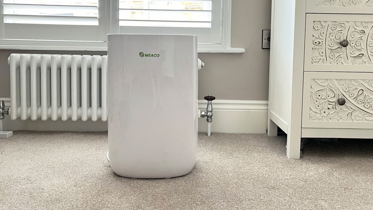 image of MeacoDry ABC 12L dehumidifier in room with white column radiator, cream ornate chest of drawers and window with white shutters