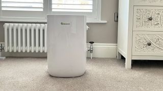 image of MeacoDry ABC 12L dehumidifier in room with white column radiator, cream ornate chest of drawers and window with white shutters