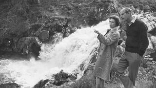 Queen Elizabeth II and Prince Philip, Duke of Edinburgh by a waterfall in the grounds of Balmoral Castle, Scotland