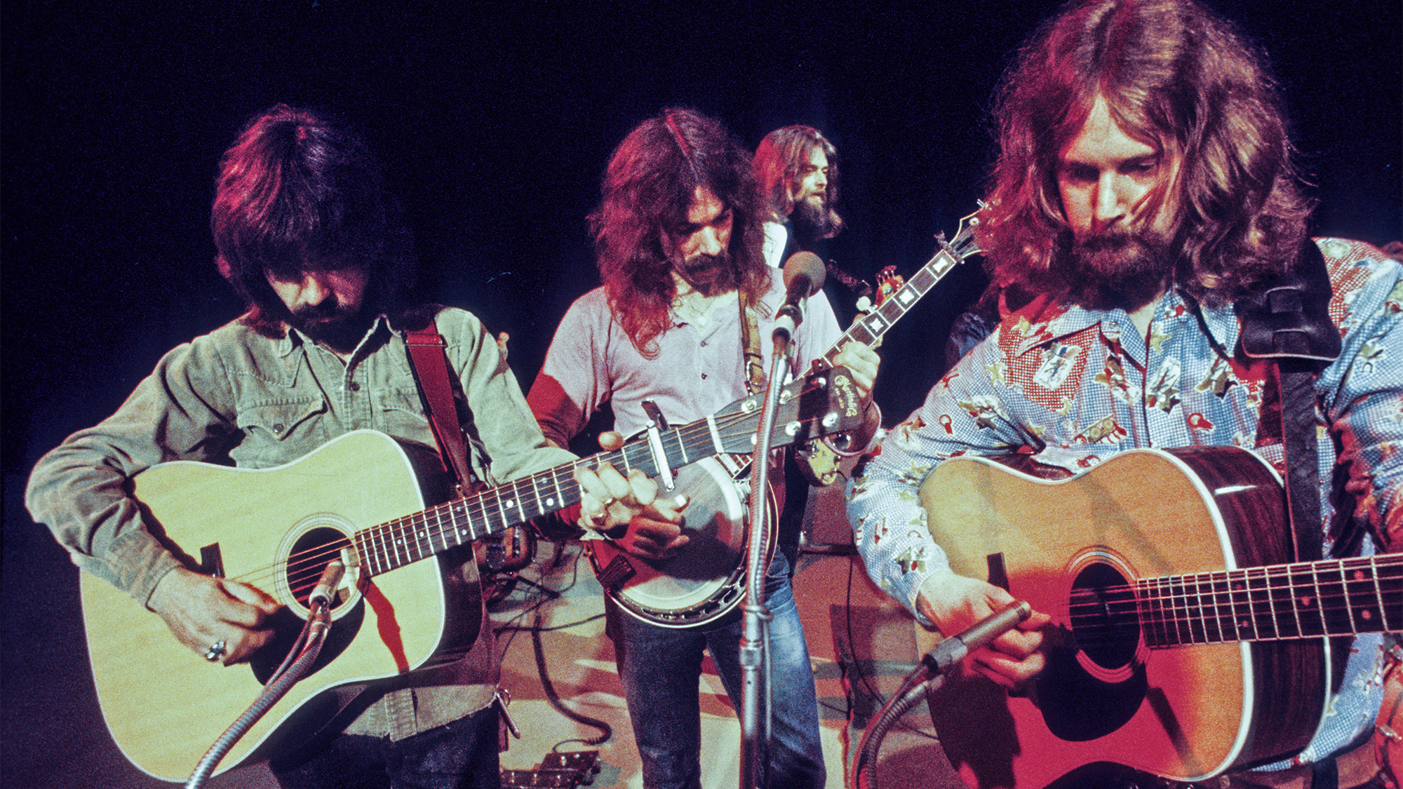 The Byrds perform live on stage in London in 1971. Left to Right: Clarence White, Gene Parsons, Skip Battin (in background) and Roger McGuinn.