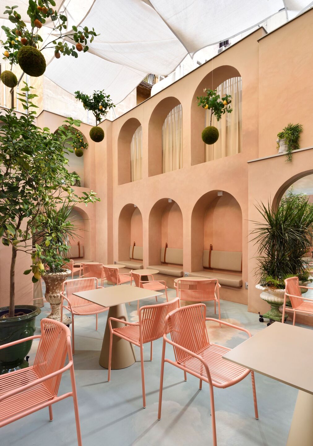 An imaginatively designed hotel's common areas feature otherworldly d&eacute;cor, including sky-like floors, pink arches and curtains, and sculptural furniture.