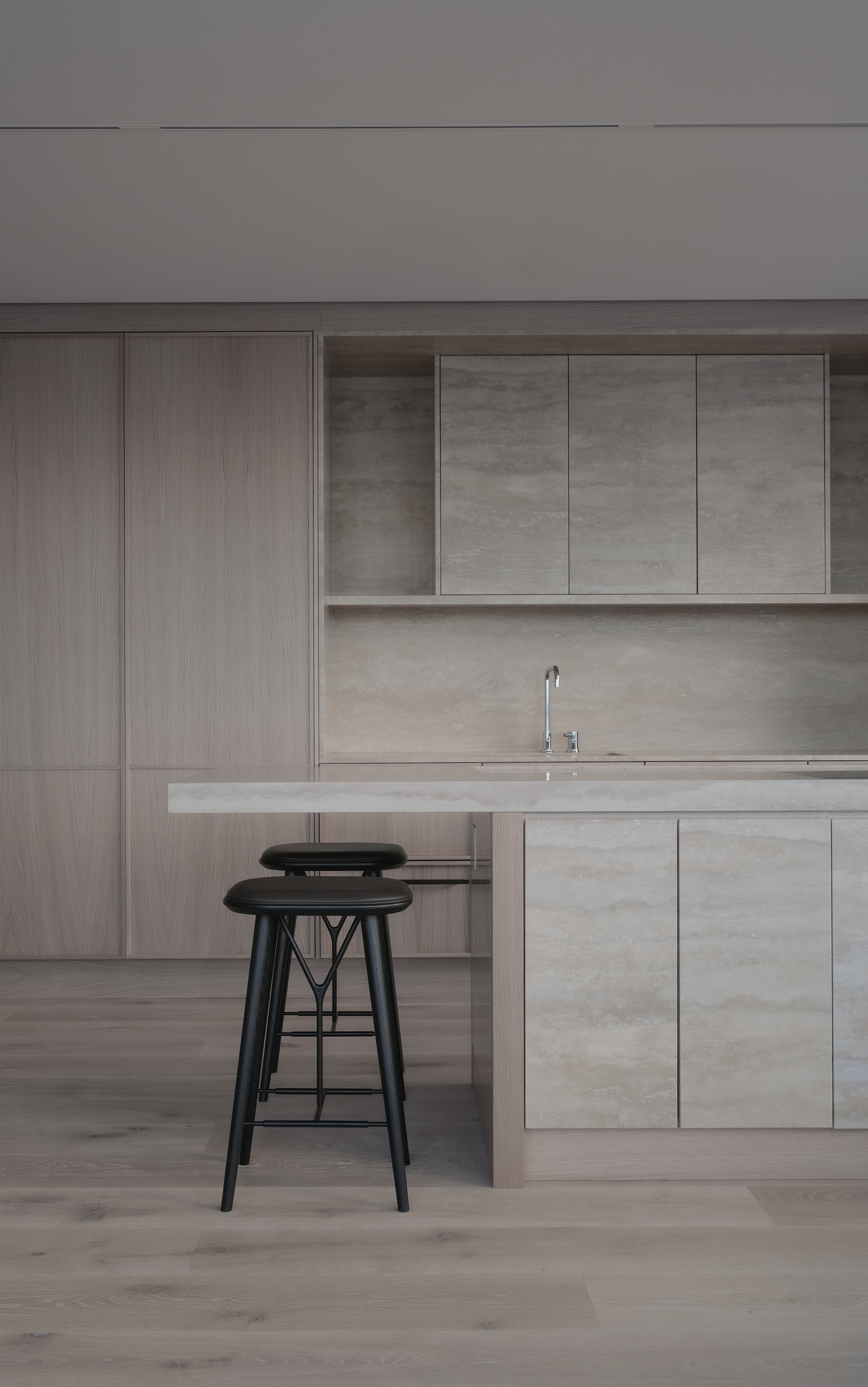 a travertine clad kitchen with pale wooden cabinets