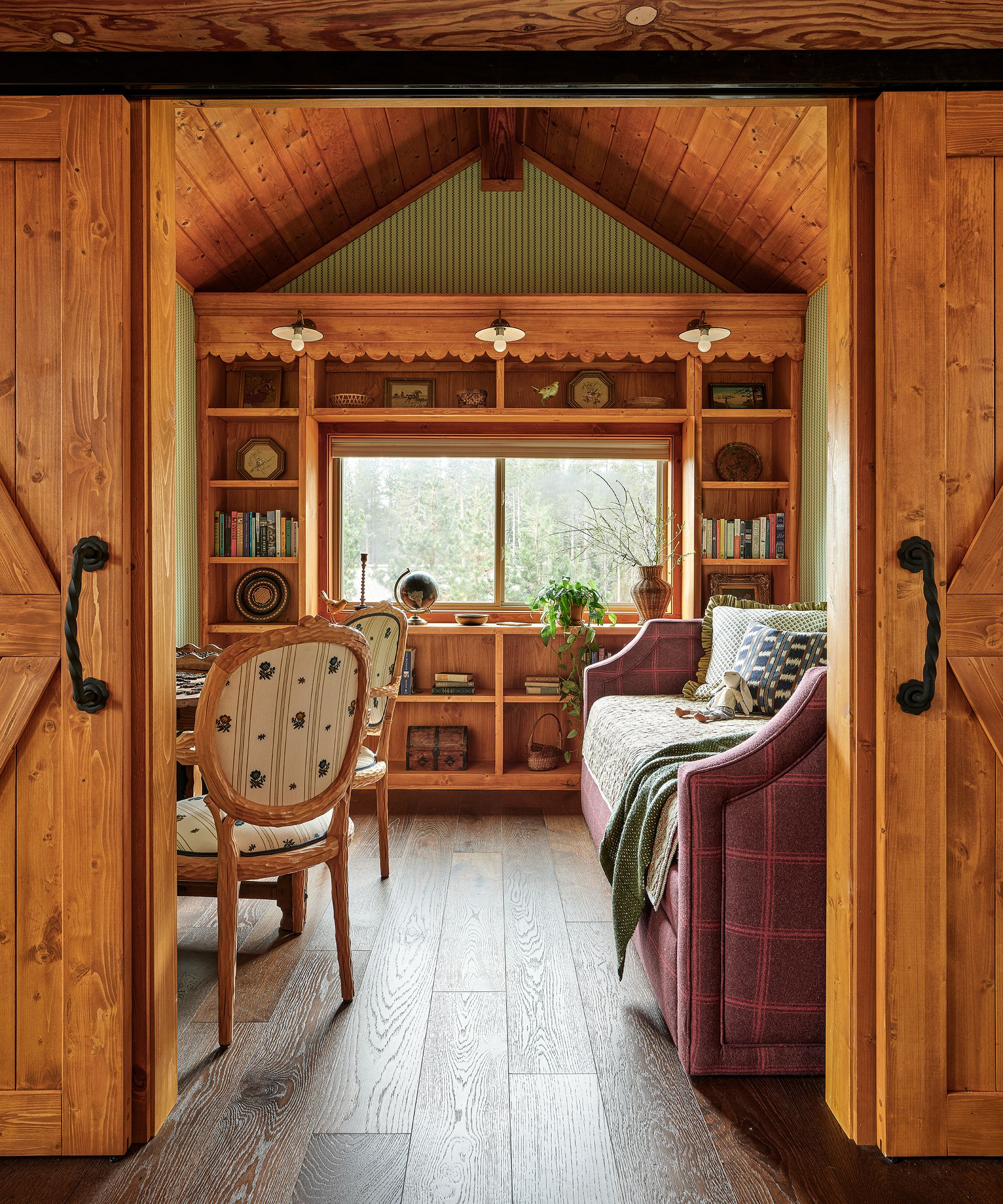a loft 'bonus room' with vaulted wood clad ceiling, double sliding doors and a pine bookcase wall with a plaid day bed