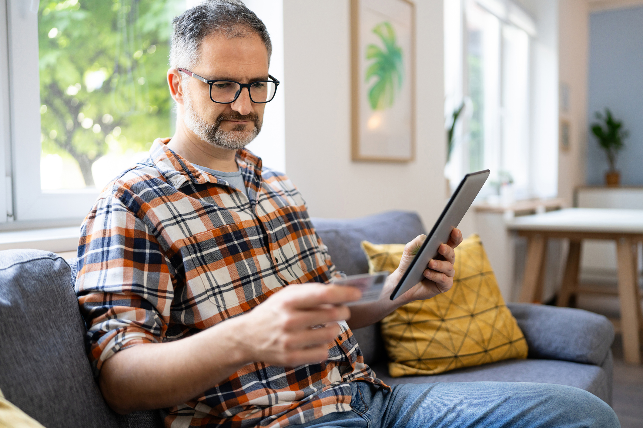 Man typing his social security number over a digital tablet from home.