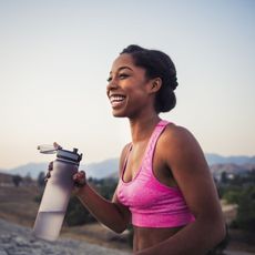 happy female runner holding water bottle