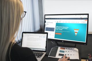 woman on laptop with monitor displaying sales funnel
