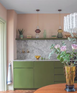 An example of kitchen cabinet ideas showing green cabinets with a shelf above