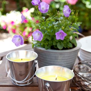 A garden table with a flowering plant and two burning candles