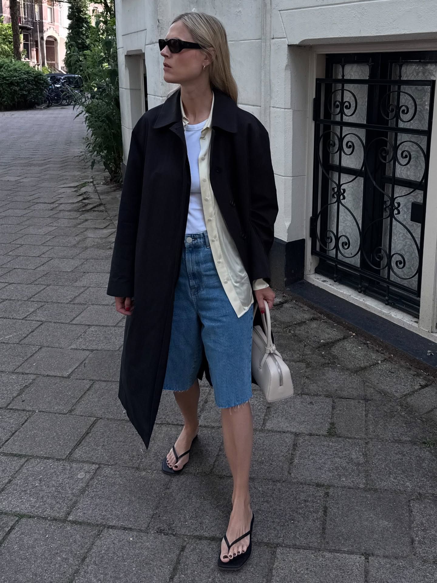 An image of @ lindatol_ wearing denim shorts trousers, one of the best anti-jeans summer trouser trends, with a tank top and scarf belt.