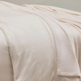 Shleep Luxury Merino Wool Bedding on a bed against a gray background.
