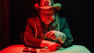 Marcus King at a poker table wearing a cowboy hat