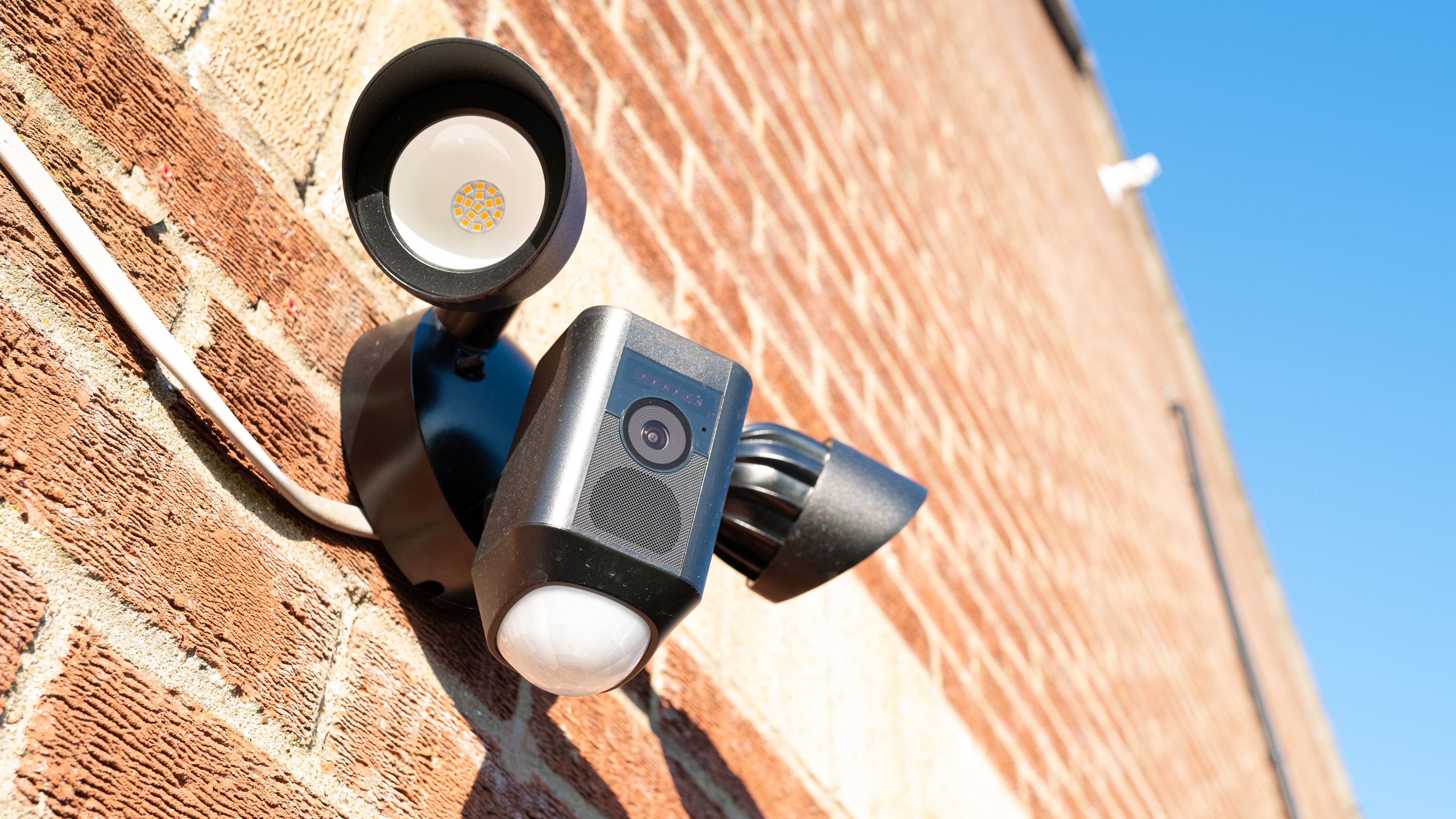 Home security camera with PIR detector and two LED floodlights on a side entrance to a house