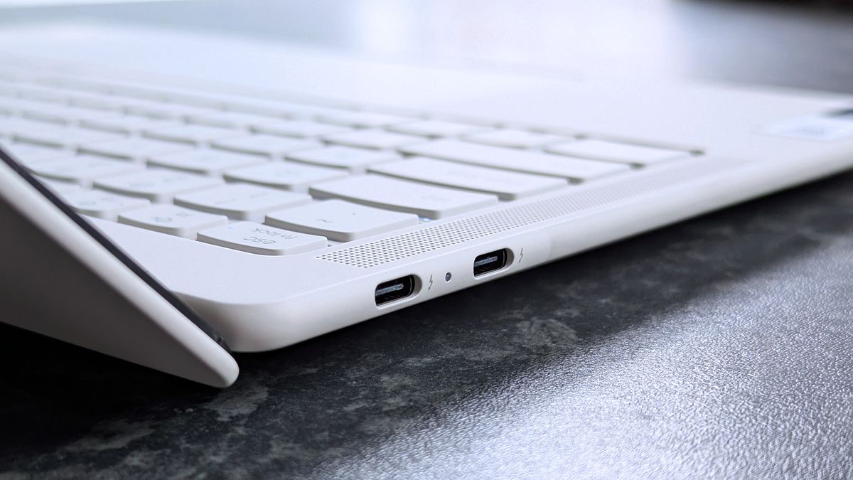 Close-up of a Lenovo Yoga Slim 7i Ultra (Gen 11) Aura Edition laptop resting on a dark surface, highlighting two USB-C ports on the side.