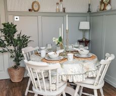 A dining room with sage green walls with waitscoting and bobbin molding 