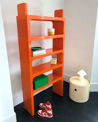Red plastic shelving unit by Kartell, on a black wooden floor