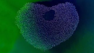 A large flock of flamingos forms a heart shape over a vibrant green lake. The peaceful scene and natural symmetry create a sense of harmony and beauty