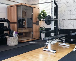 Home gym idea with weight rack bench yoga mats and foam rollers in a basket and sauna