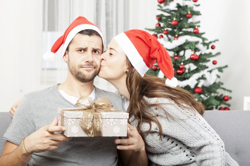 Two people wearing Santa hats exchanging gifts