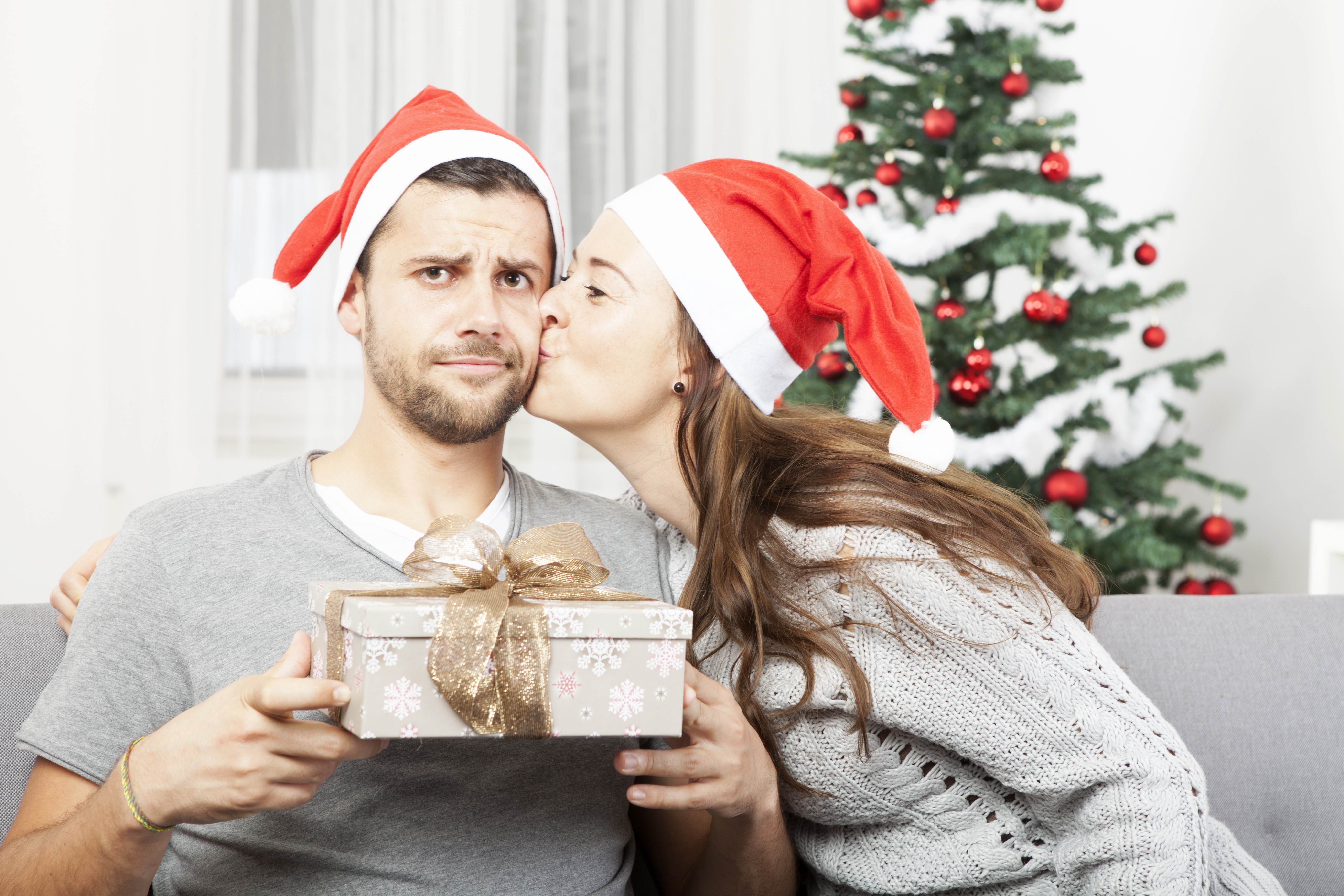 Two people wearing Santa hats exchanging gifts