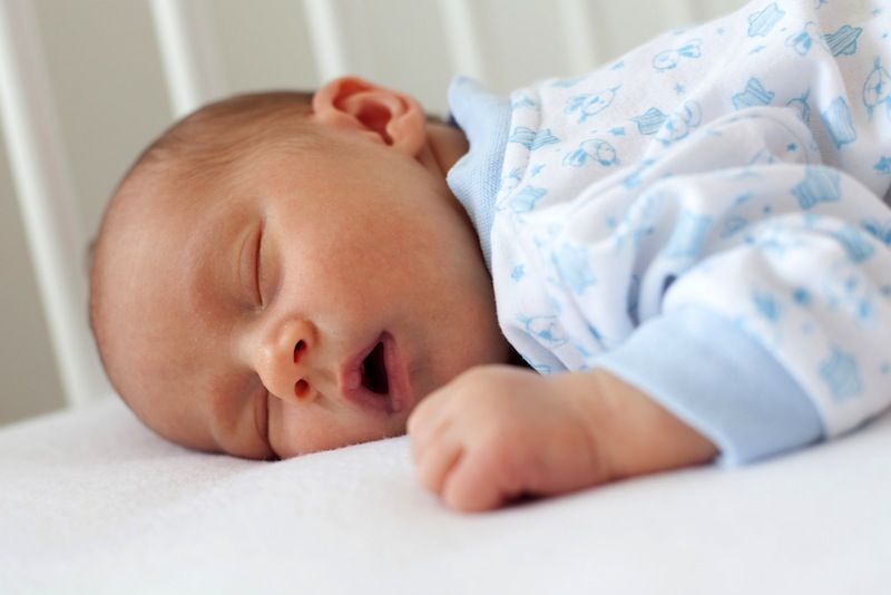 A baby sleeps in his crib.