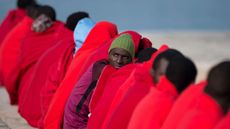 Migrants keep warm with Red Cross blankets upon their arrival at Malaga harbour this year