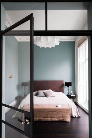 Pale blue bedroom with pink bedding and glass wall partition