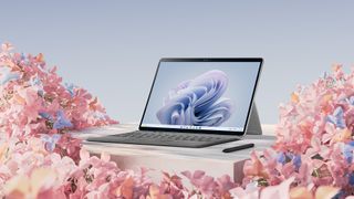 A Microsoft Surface Pro 9, with a blue background, sitting on pink flowers.