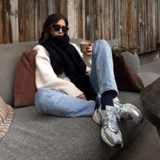 @_jessicaskye wears silver-accent trainers with blue jeans, a cream jumper and a black scarf