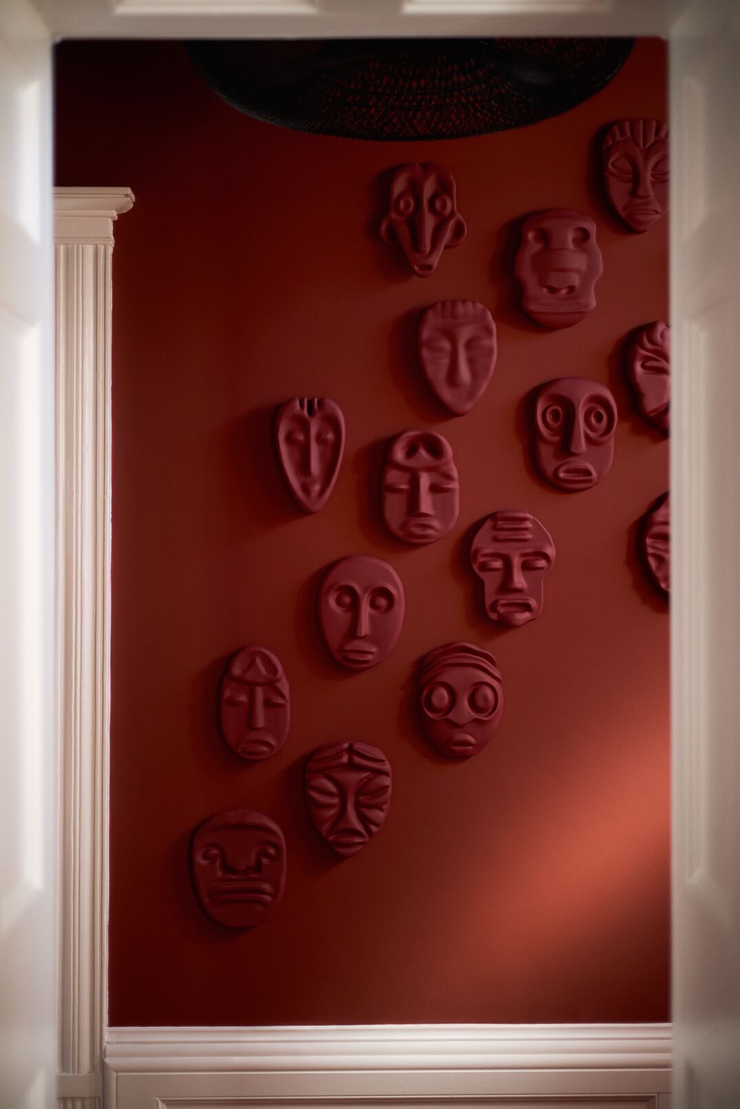 A series of shots capturing a young man dressed in patterned, or color-blocky, clothing, either standing in the sun-lit outdoor areas of a lush hotel, or inside a colorfully decorated suite filled with collectibles, artworks, and textural touches, or the interiors of that very space.