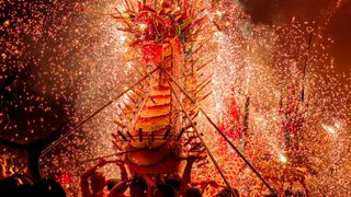 A vibrant dragon dance at a festival, surrounded by a shower of golden sparks from fireworks, people carry the dragon
