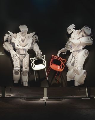 Two robots present the 'Masters' chairs