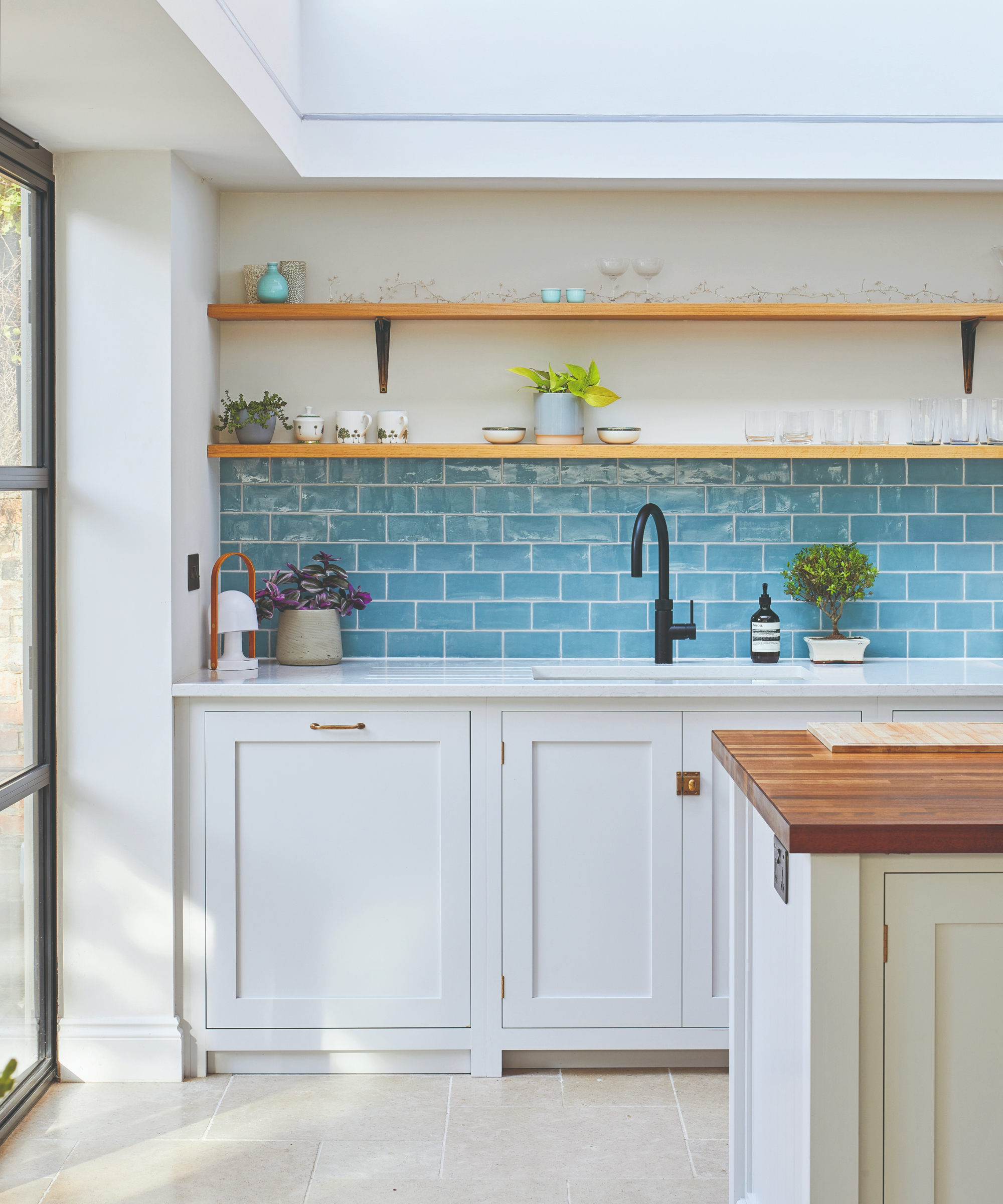 Kitchen with white cabinets, wooden worktop and blue splashback
