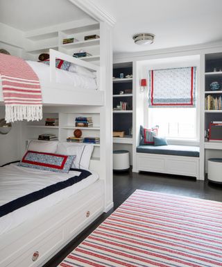 A kids bedroom with white bunk beds and blue and red soft furnishings