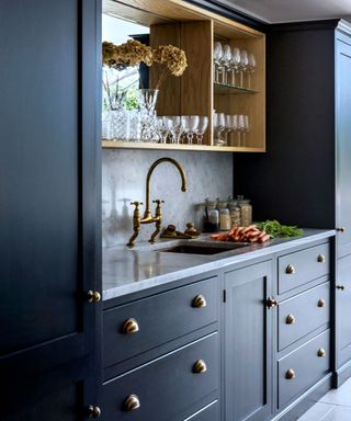 Dark blue kitchen cupboards with kitchen sink, marble worktop and splashback.